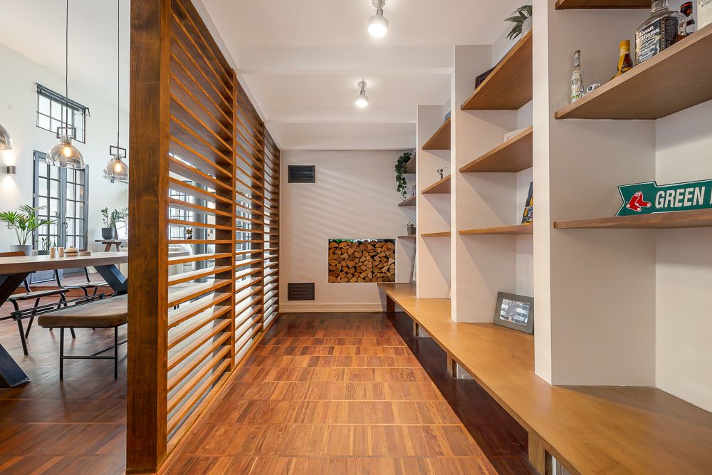 Moderner Raum mit Holzregalen, Sitzbank, Holzlattenwand und Blick auf Esszimmer.
