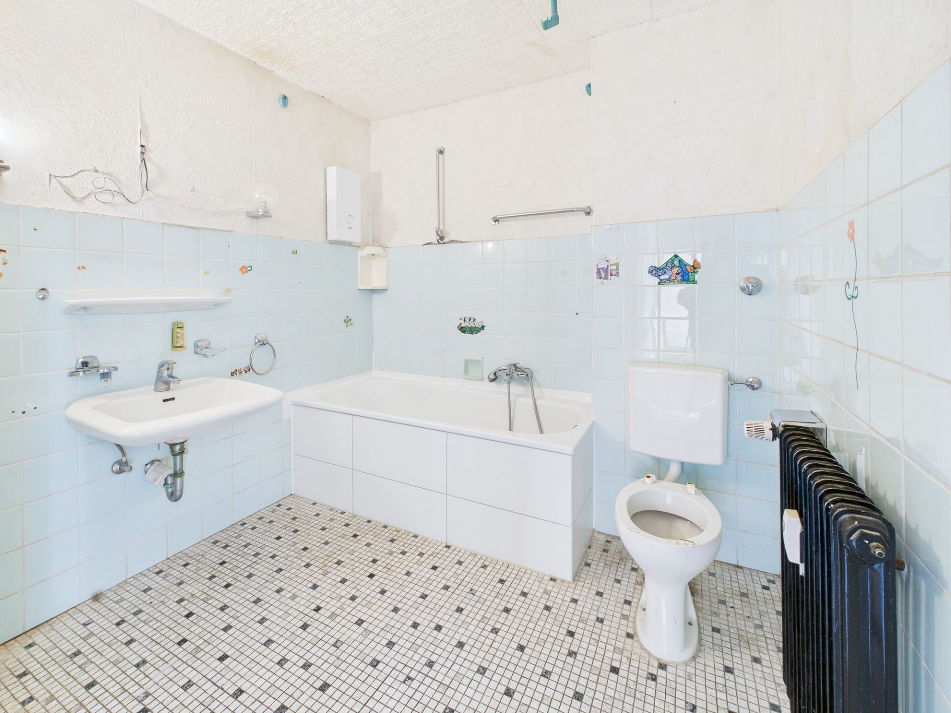 Helles Badezimmer mit Badewanne, Waschbecken, Toilette und weiß-blauen Fliesen.