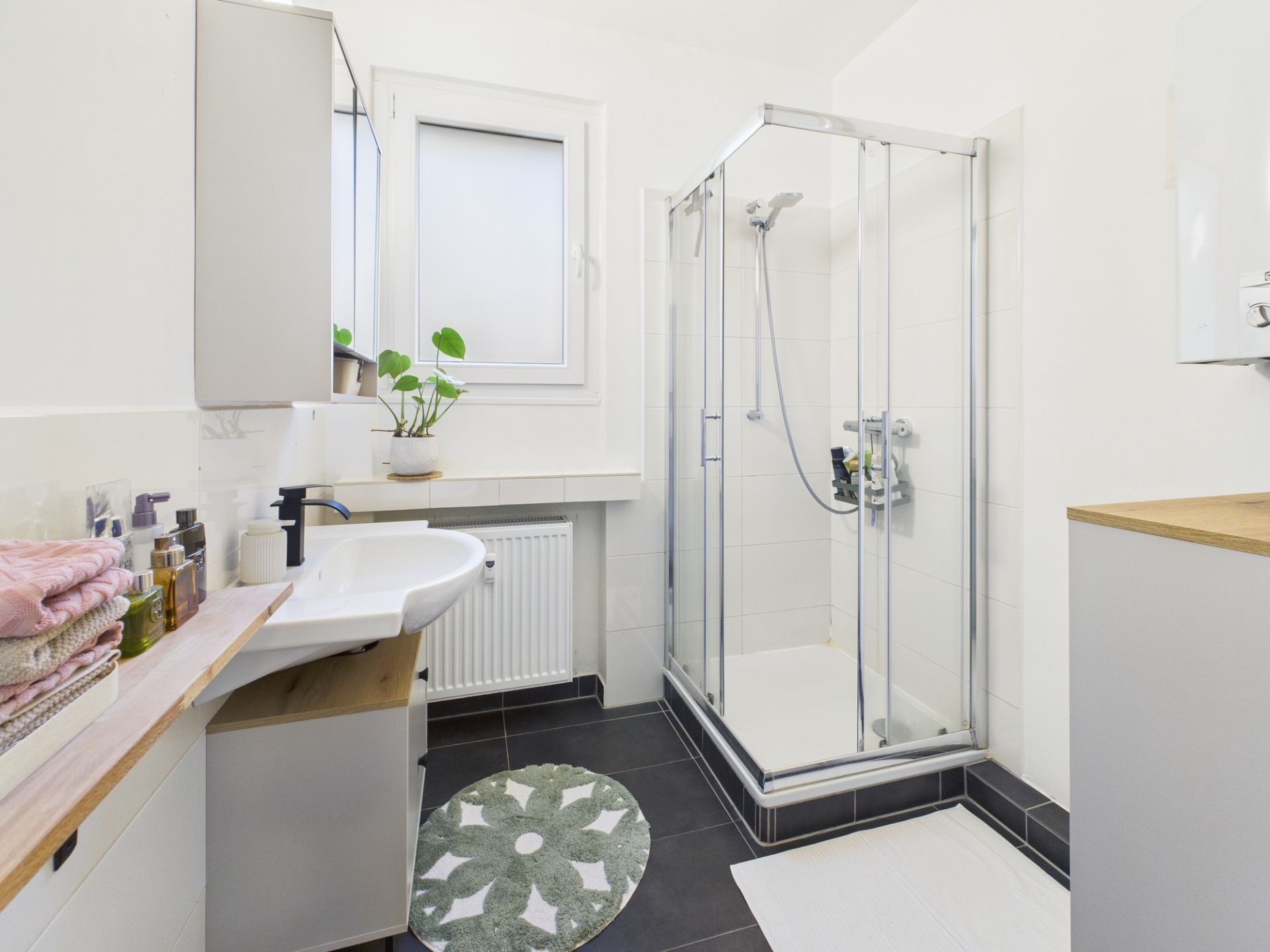 Modernes Badezimmer mit Dusche, Waschbecken, Spiegelschrank und Fenster.