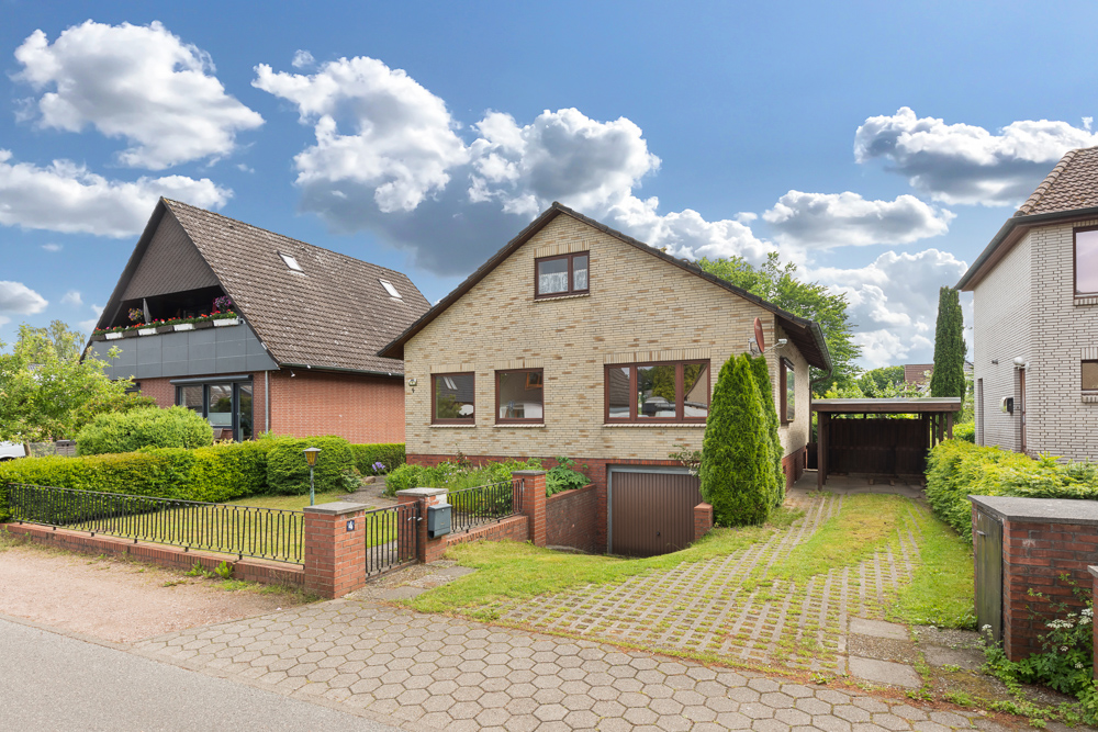 Einfamilienhaus mit Ziegeldach, Garage und Carport, von Vorgarten und Auffahrt umgeben.