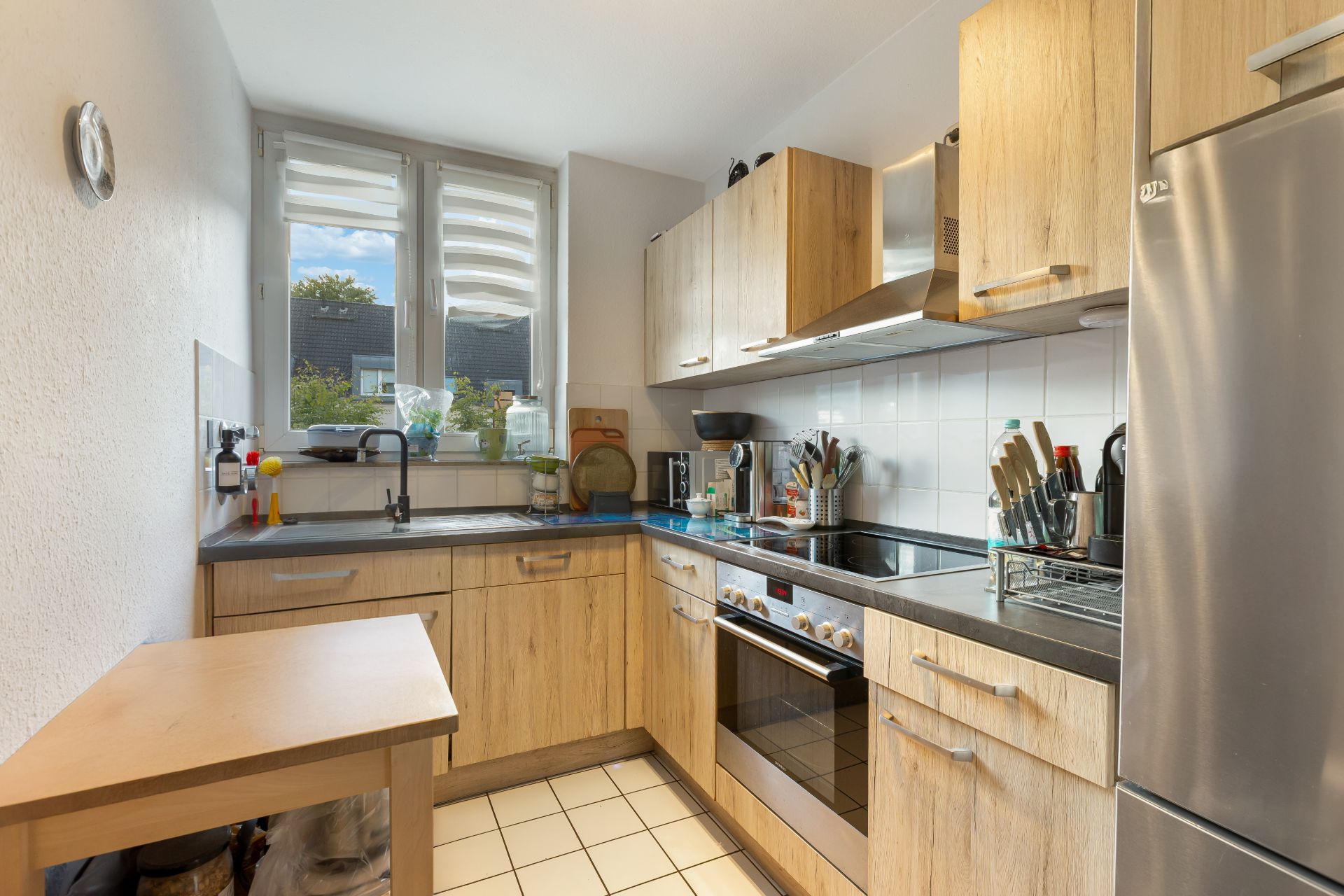 Moderne Küche mit Holzschränken, Elektroherd und großem Fenster.