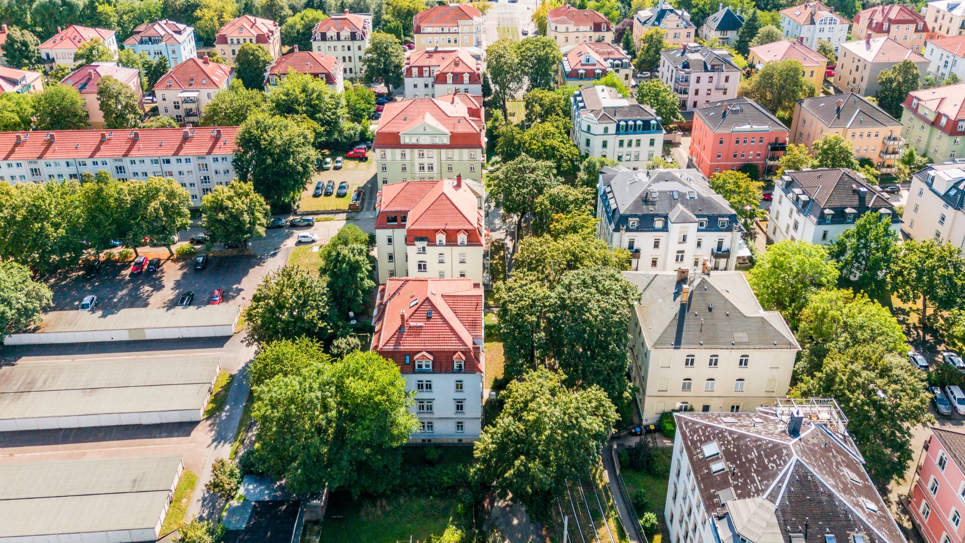 Luftaufnahme von mehreren Wohnhäusern mit roten Dächern und vielen Bäumen dazwischen.