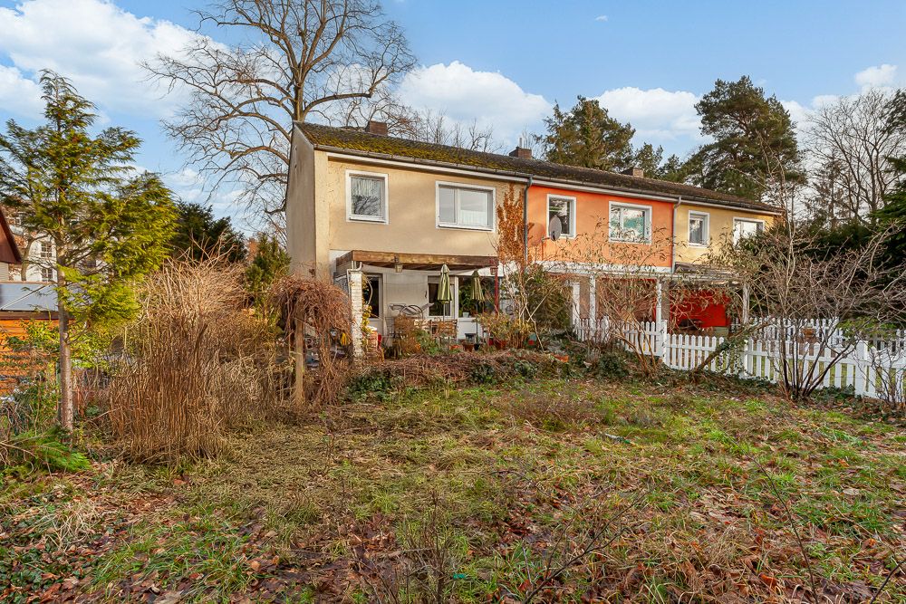 Rückseite eines zweistöckigen Reihenhauses mit großem Garten und Terrasse.