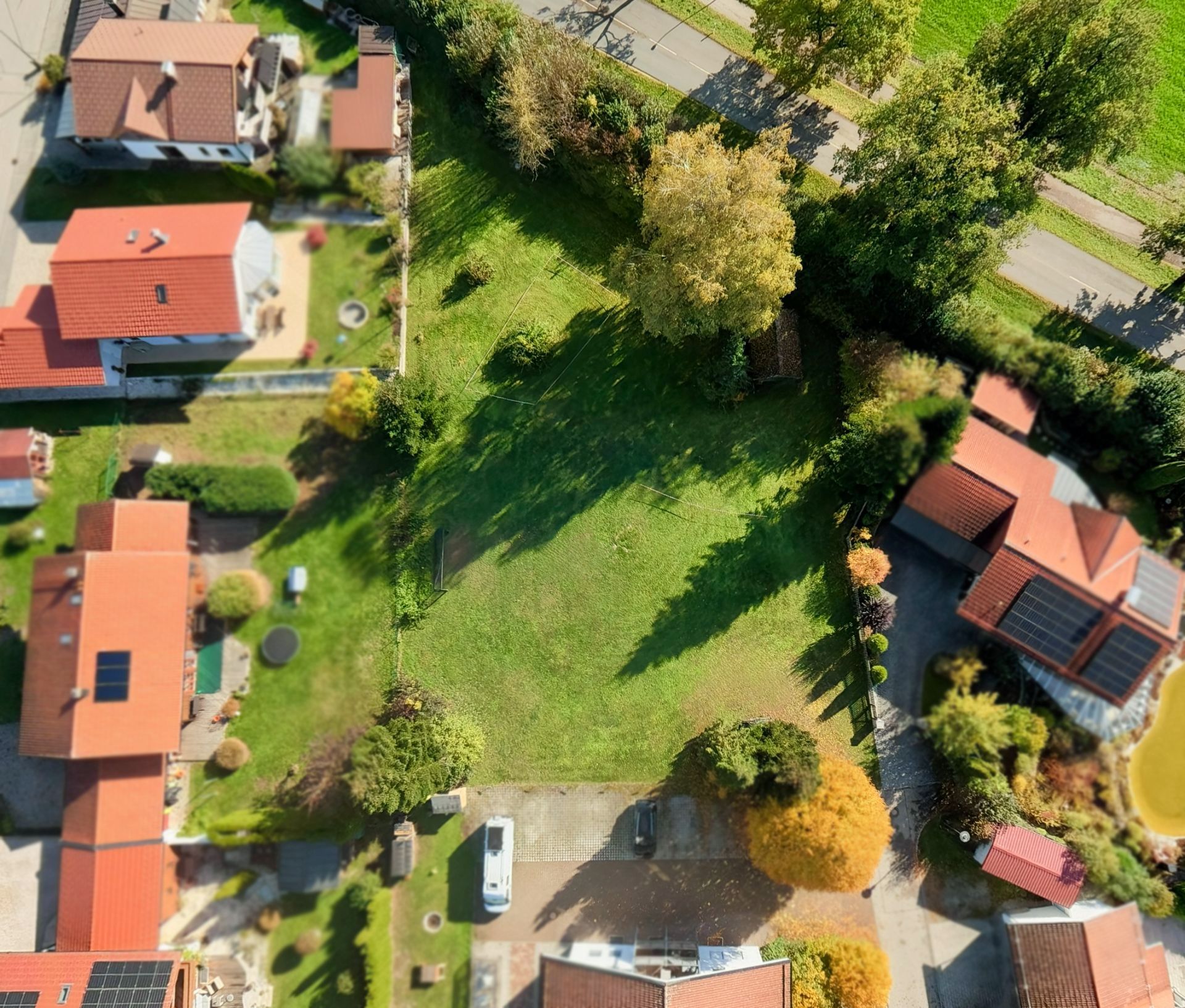 Luftaufnahme eines Wohngebiets mit mehreren Häusern und großem grünen Garten in der Mitte.
