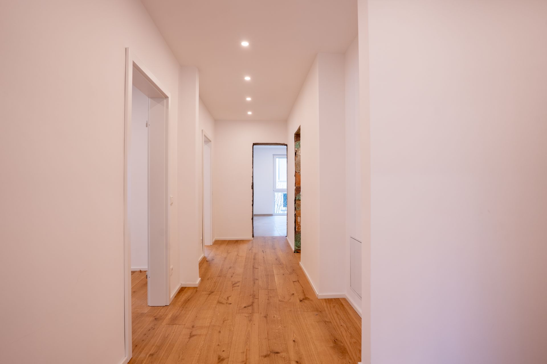 Heller Flur mit Holzfußboden und mehreren Türen in einer Wohnung.