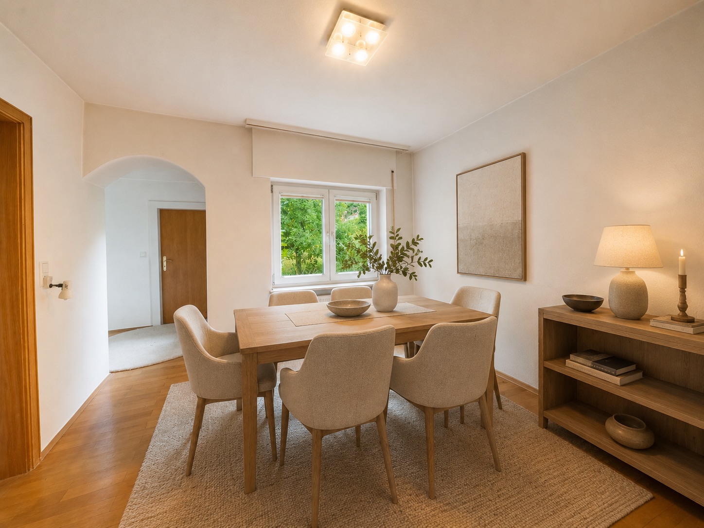 Esszimmer mit Holztisch, sechs Stühlen, Regal, Lampe und großem Fenster mit Blick ins Grüne.