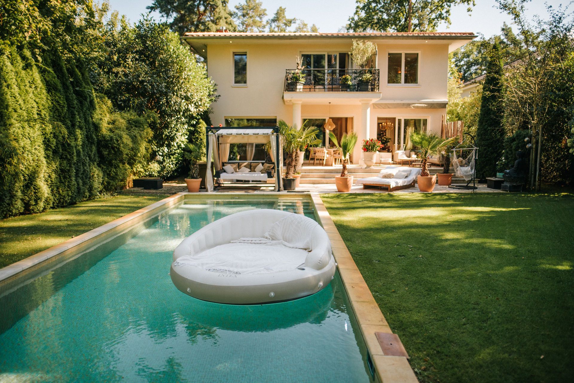 Modernes Wohnhaus mit Pool, Rasen und aufblasbarer Liege im Garten.