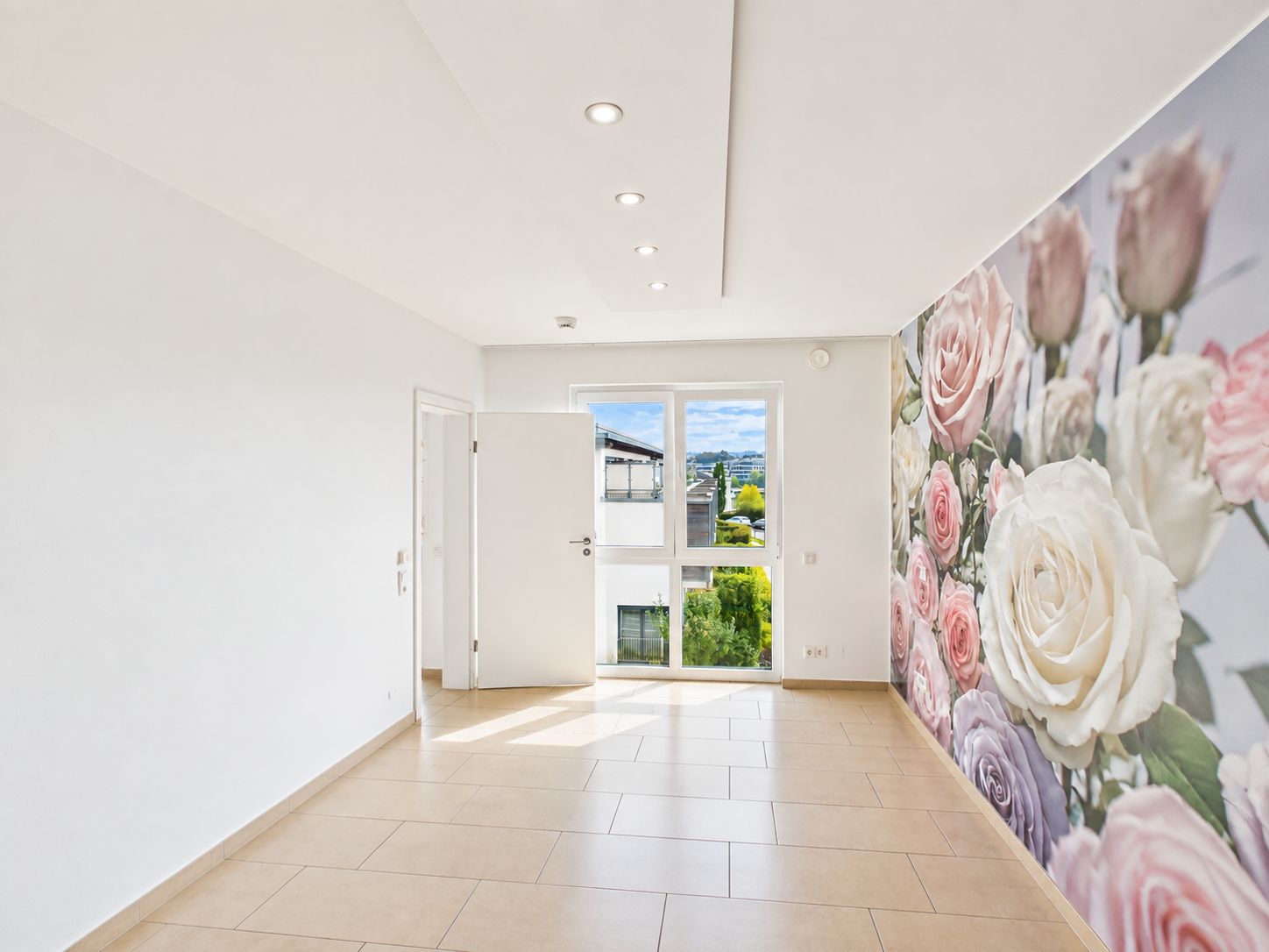 Heller Raum mit Fliesenboden, großer Fensterfront und einer Wand mit Blumenmuster.