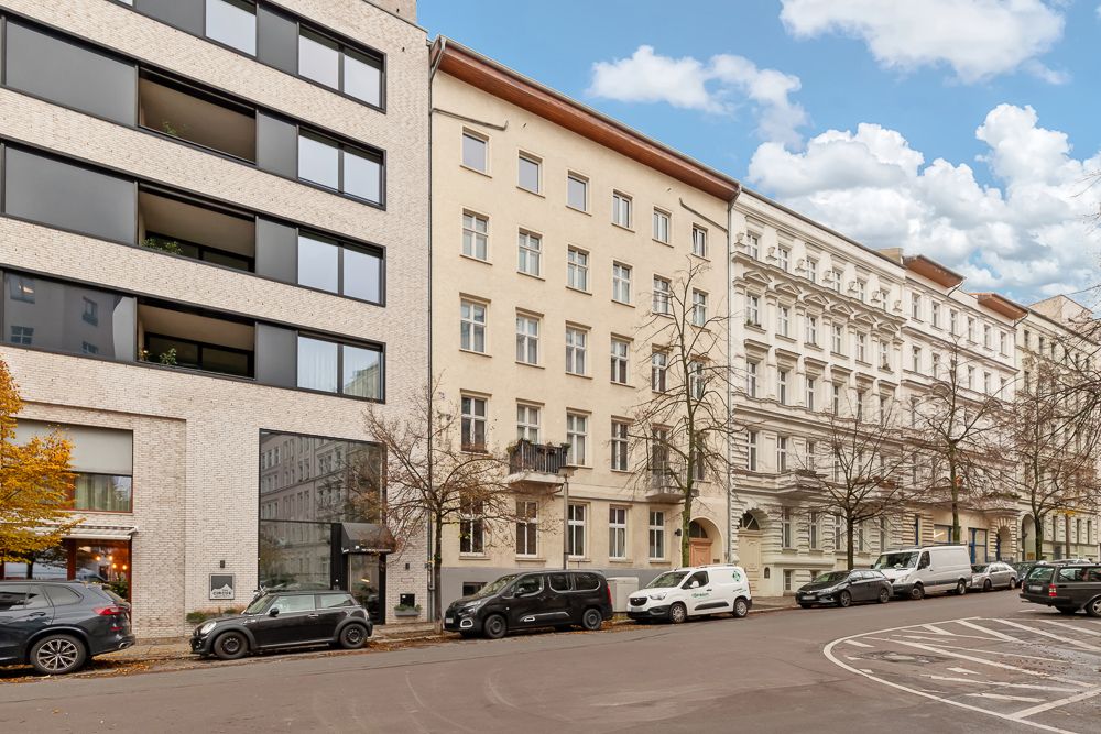 Straßenszene mit mehreren Wohnhäusern und parkenden Autos am Straßenrand.