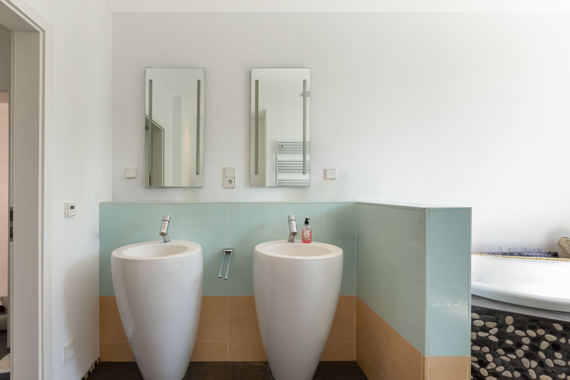 Zwei moderne Waschbecken mit Spiegeln in einem hellen Badezimmer.