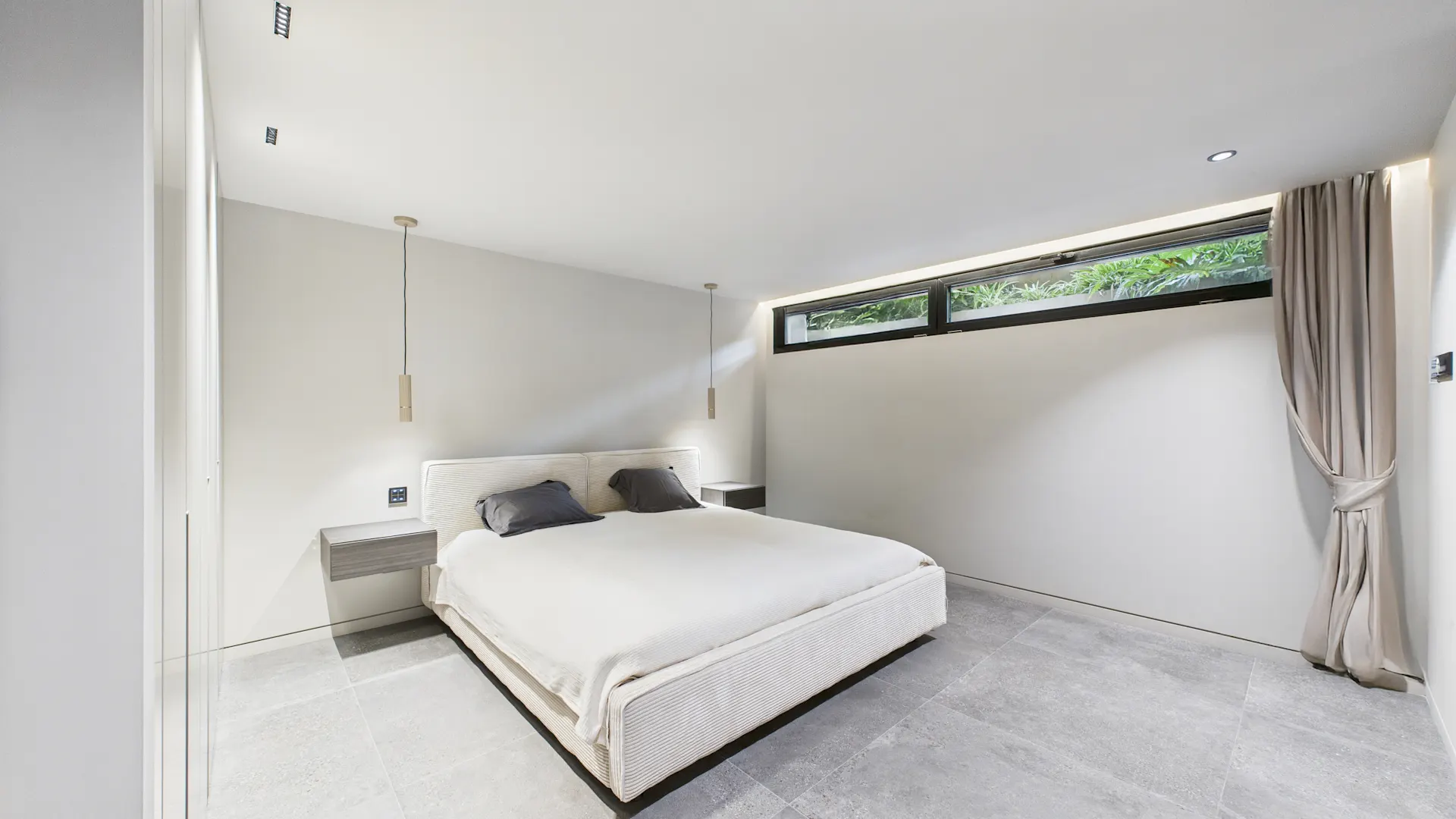 Modernes Schlafzimmer mit großem Bett, zwei Nachttischen und Fenster mit Vorhängen.