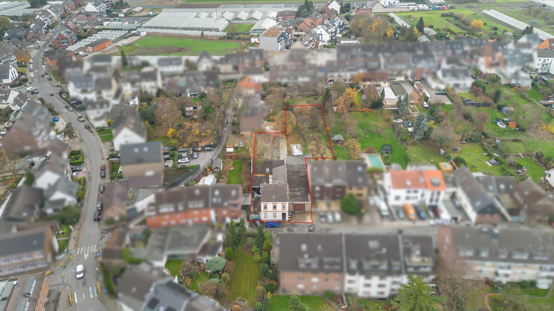 Luftaufnahme eines Wohngebiets mit Häusern, Gärten und Straßen, ein Grundstück ist rot umrandet.