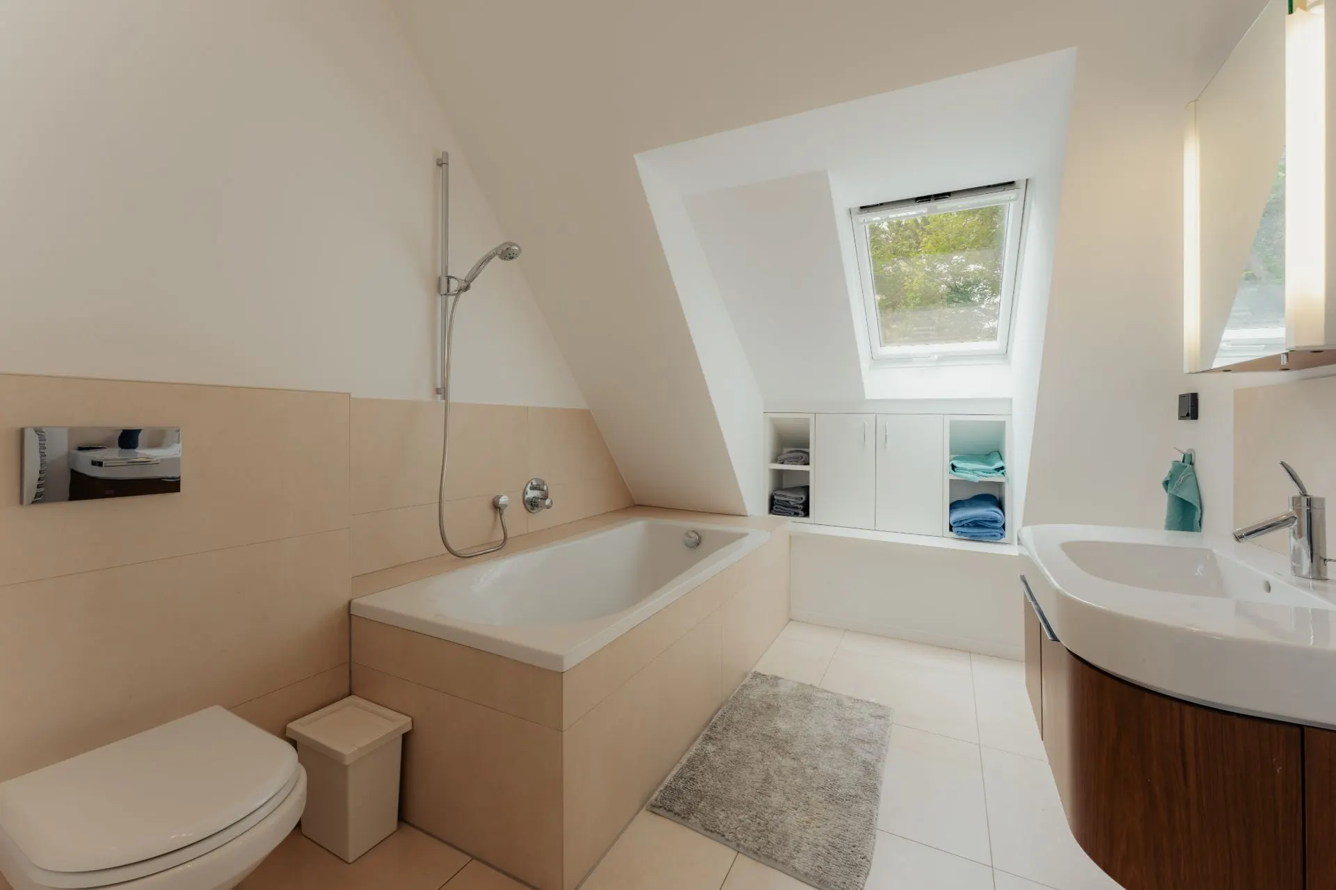Modernes Badezimmer mit Badewanne, Waschbecken, WC und Dachfenster.