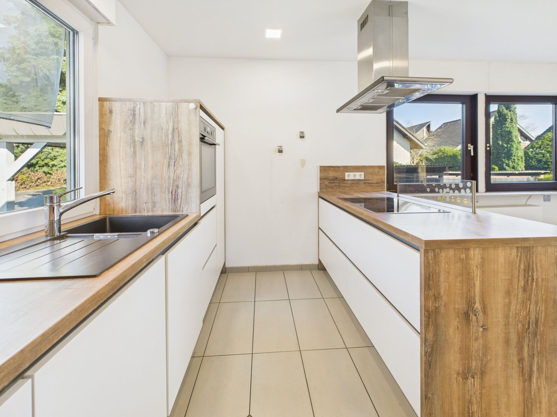 Moderne Küche mit Holz- und weißen Elementen, großem Fenster und Kochinsel.
