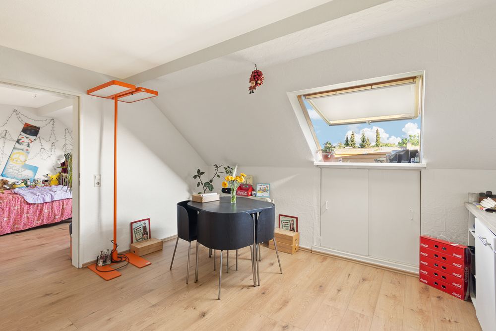 Helles Zimmer mit Esstisch, vier Stühlen, Dachfenster und Blick auf angrenzendes Schlafzimmer.