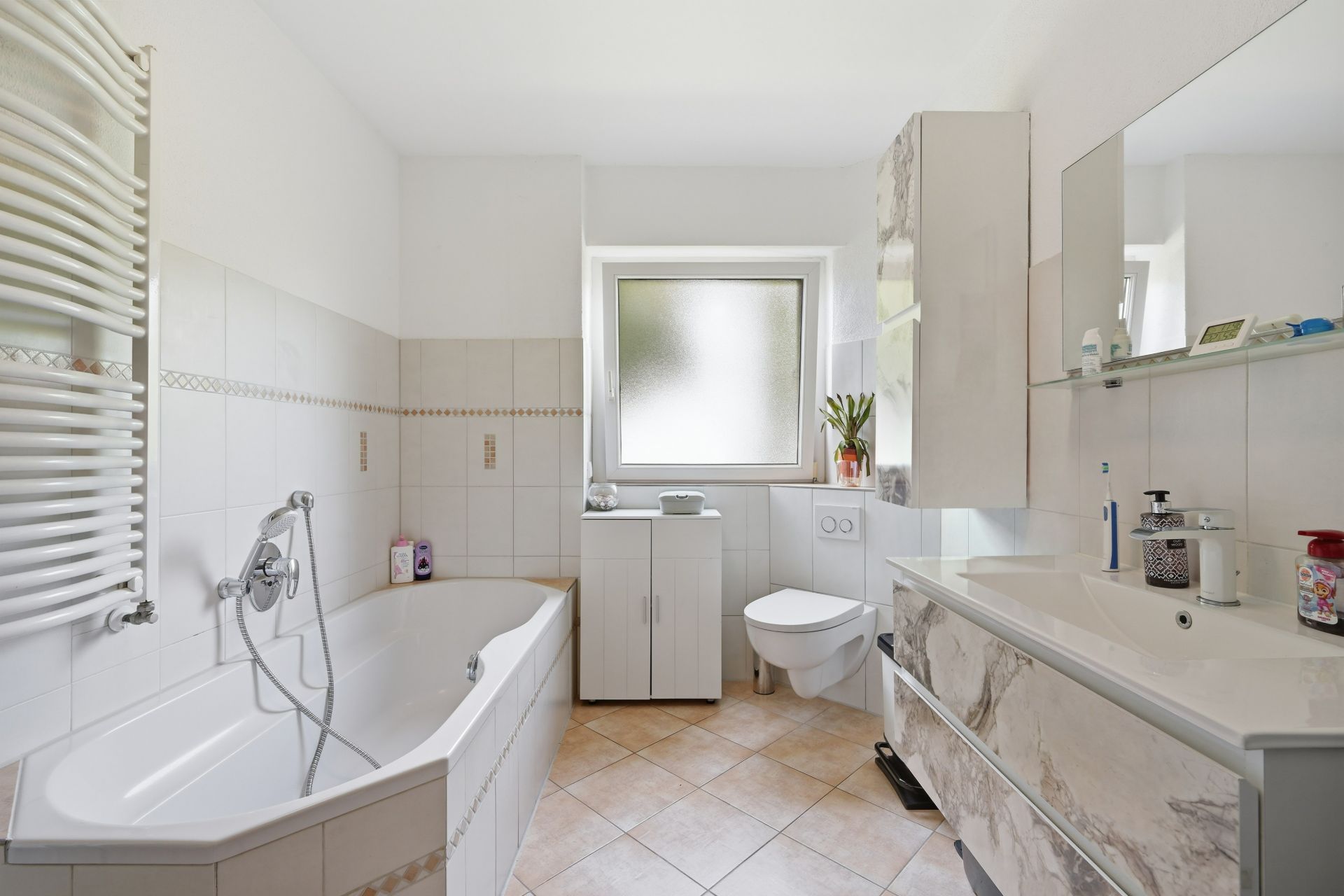 Modernes Badezimmer mit Badewanne, Waschbecken, Toilette und Fenster.
