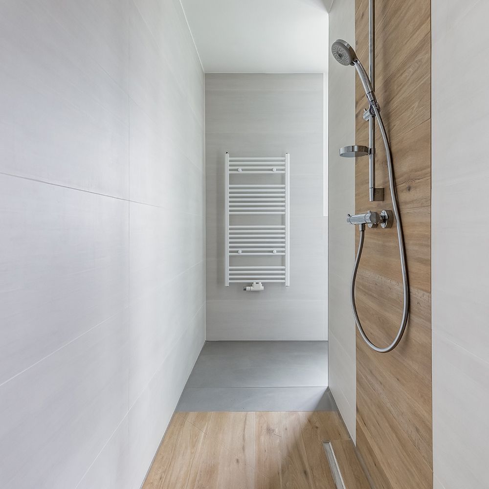 Moderne, ebenerdige Dusche mit Holzoptik-Wand und Handtuchheizkörper.