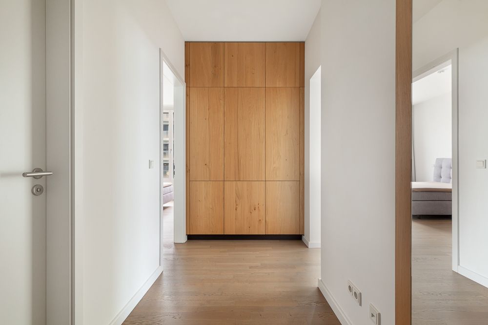 Heller Flur mit Holzboden und großem Einbauschrank aus Holz am Ende.