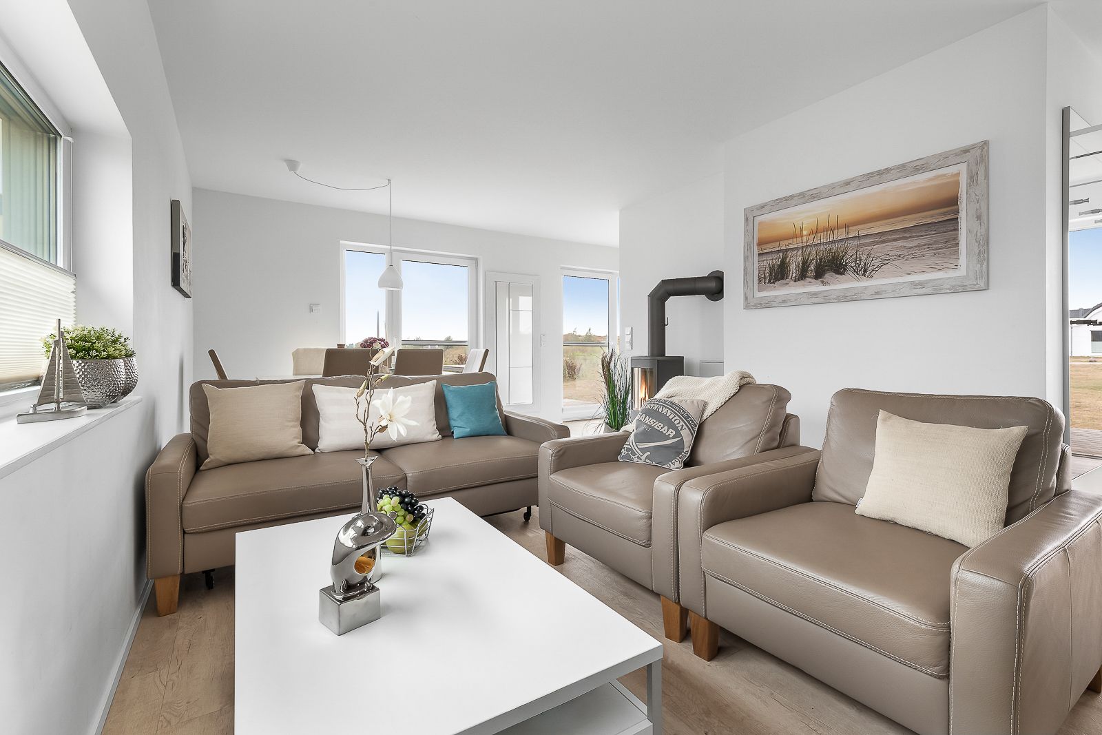 Modernes Wohnzimmer mit zwei beigefarbenen Sofas, Couchtisch, Pflanze und Wandbild.