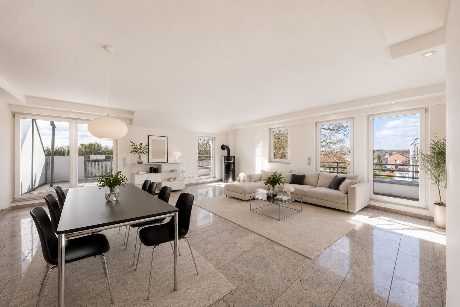Helles, modernes Wohnzimmer mit Essbereich, großen Fenstern, Sofa und Esstisch mit sechs Stühlen.