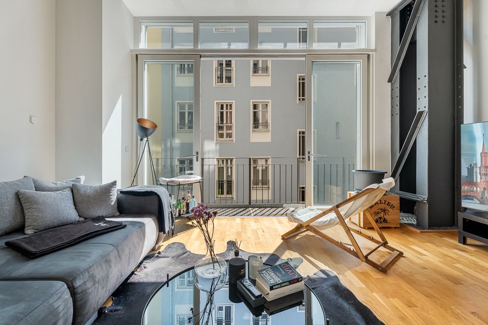Modernes Wohnzimmer mit Sofa, Sessel, Couchtisch und großem Fenster mit Blick auf Innenhof.
