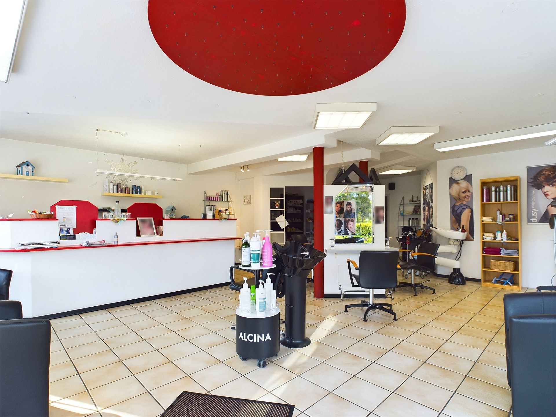 Heller Raum mit Friseurstühlen, Spiegeln, Regalen und Pflegeprodukten.