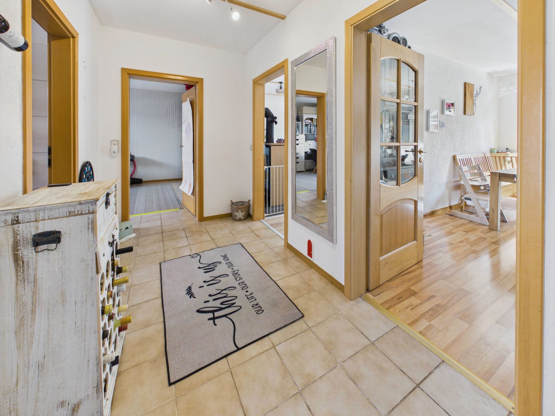 Heller Flur mit Spiegel, Holztüren und Fliesenboden in einem Wohnhaus.