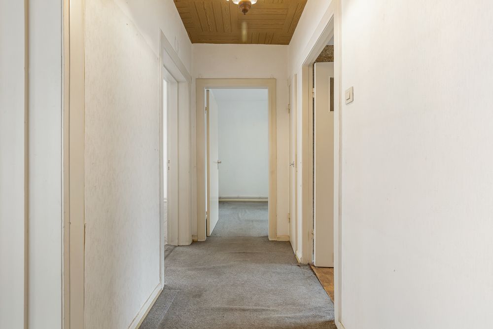 Heller Flur mit Teppichboden und mehreren offenen Türen in einer Wohnung.