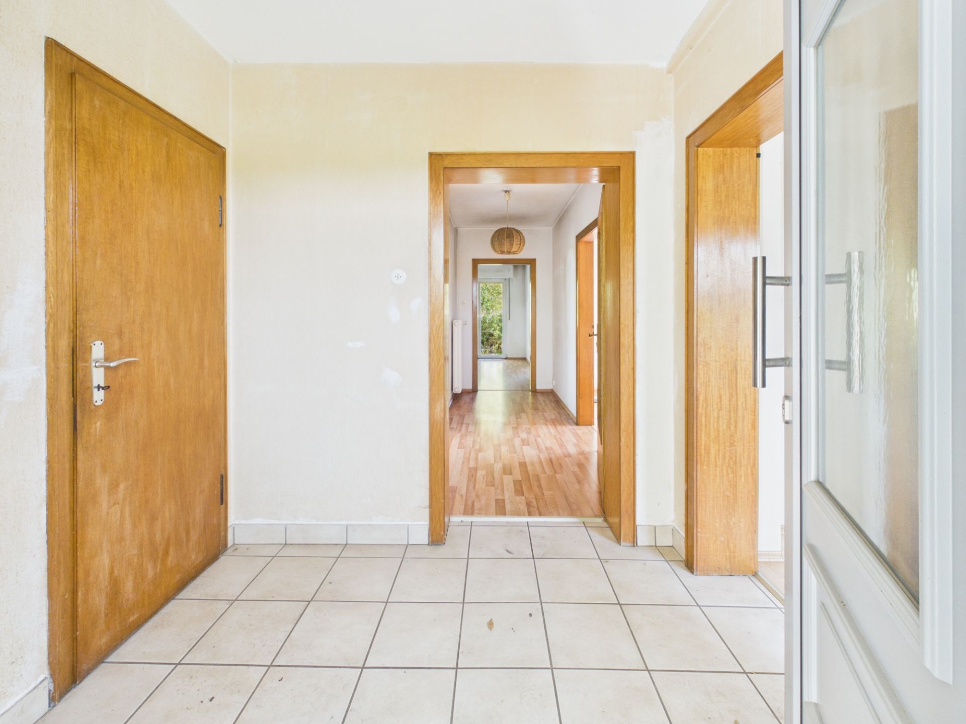 Heller Flur mit Fliesenboden und mehreren Holztüren in einem Wohnhaus.