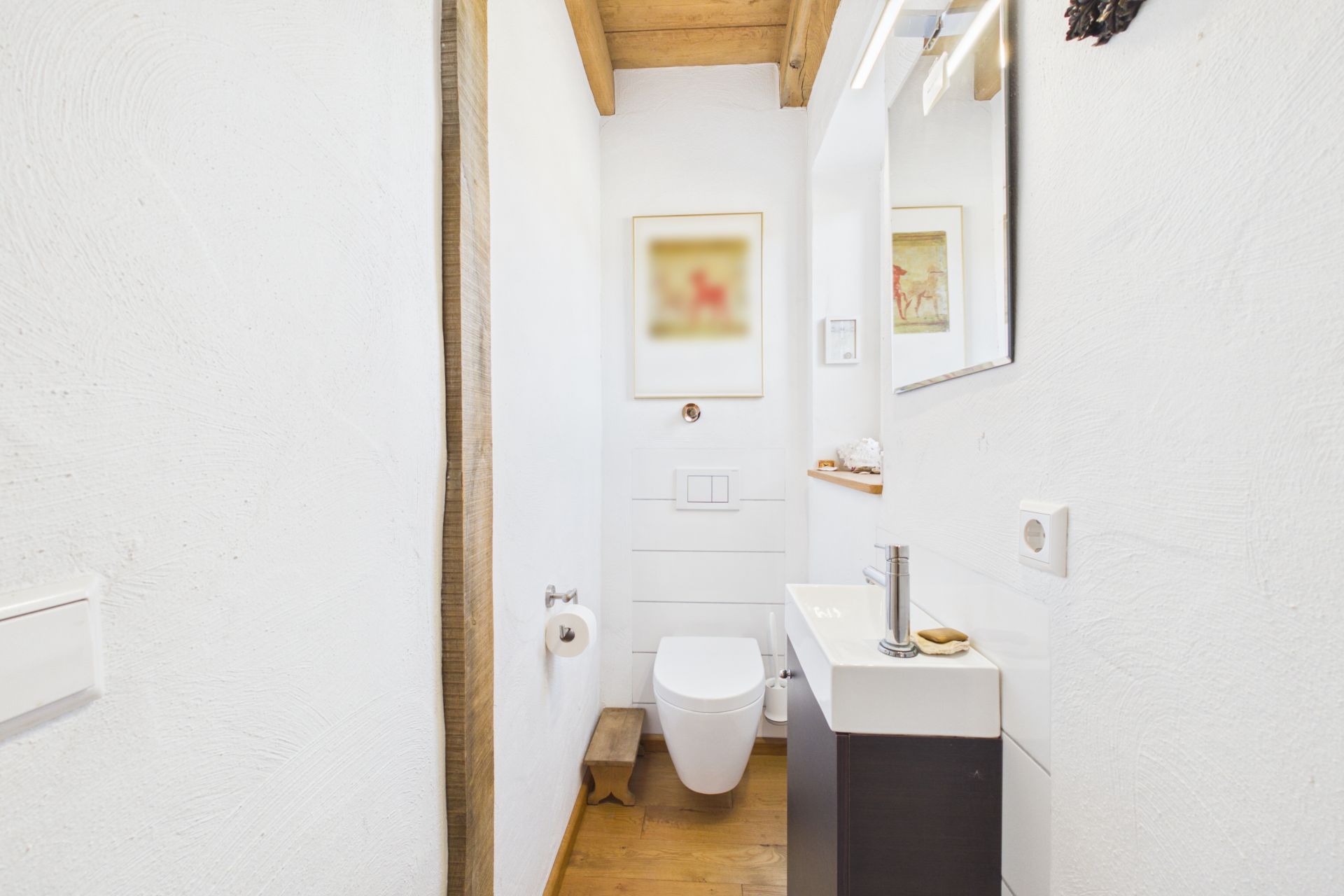 Modernes, schmales Badezimmer mit WC, Waschbecken, Spiegel und Holzboden.