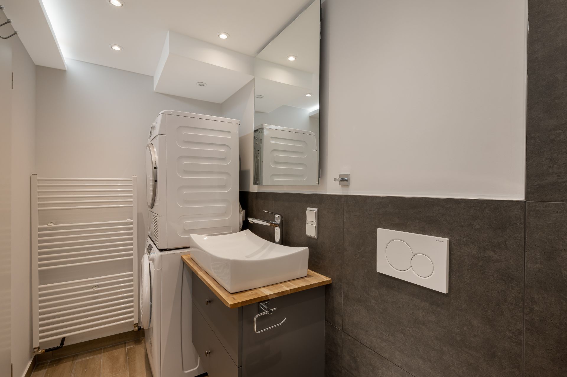 Modernes Badezimmer mit Waschbecken, Spiegelschrank und gestapelter Waschmaschine und Trockner.