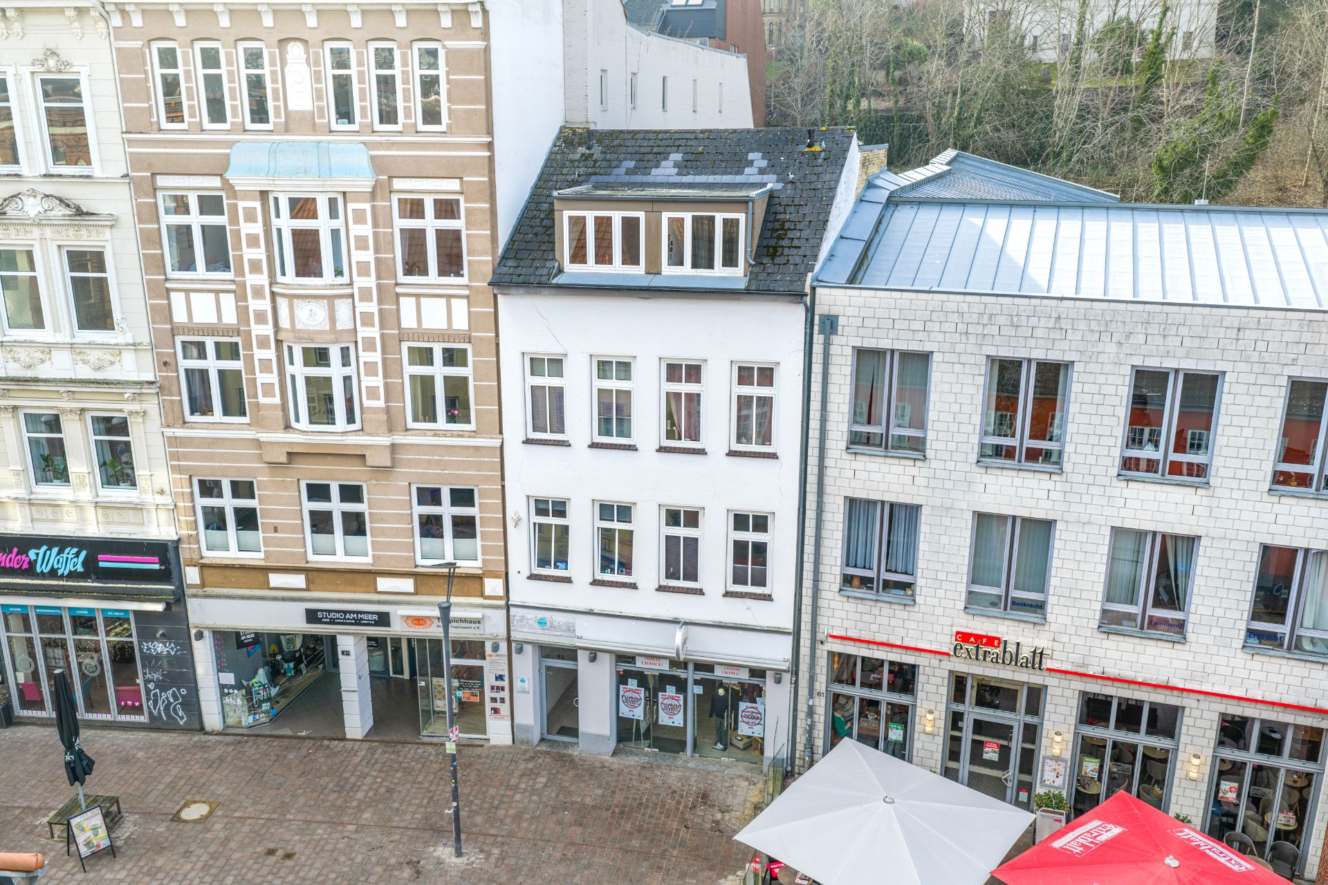 Mehrstöckiges Wohngebäude mit großen Fenstern und Geschäften im Erdgeschoss.