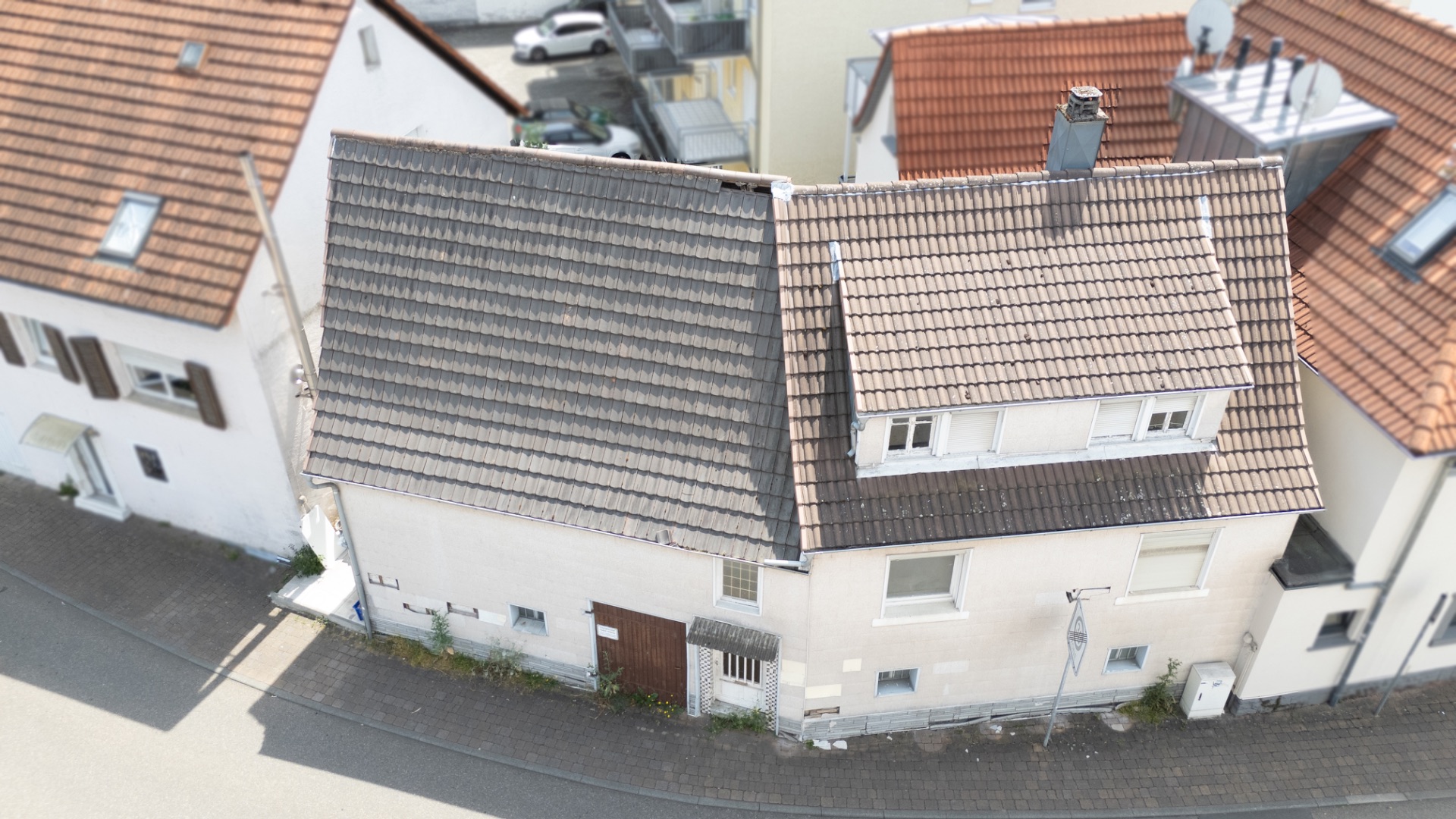 Ansicht eines Wohnhauses mit rotem Dachziegel auf einer Straßenecke.