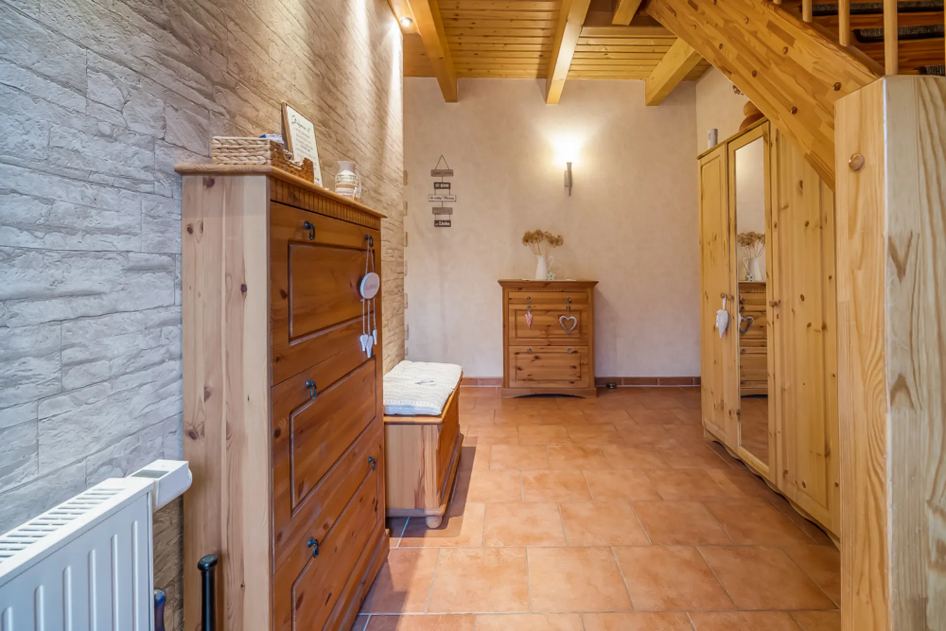 Flur mit Holzmöbeln, Fliesenboden und Treppe aus Holz in privatem Wohnhaus.