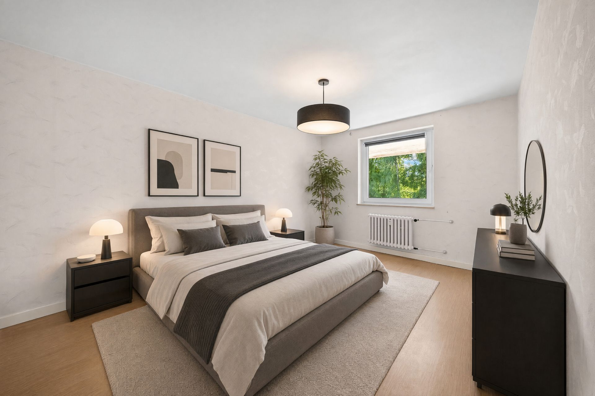 Helles Schlafzimmer mit großem Bett, Nachttischen, Kommode und Fenster mit Blick ins Grüne.