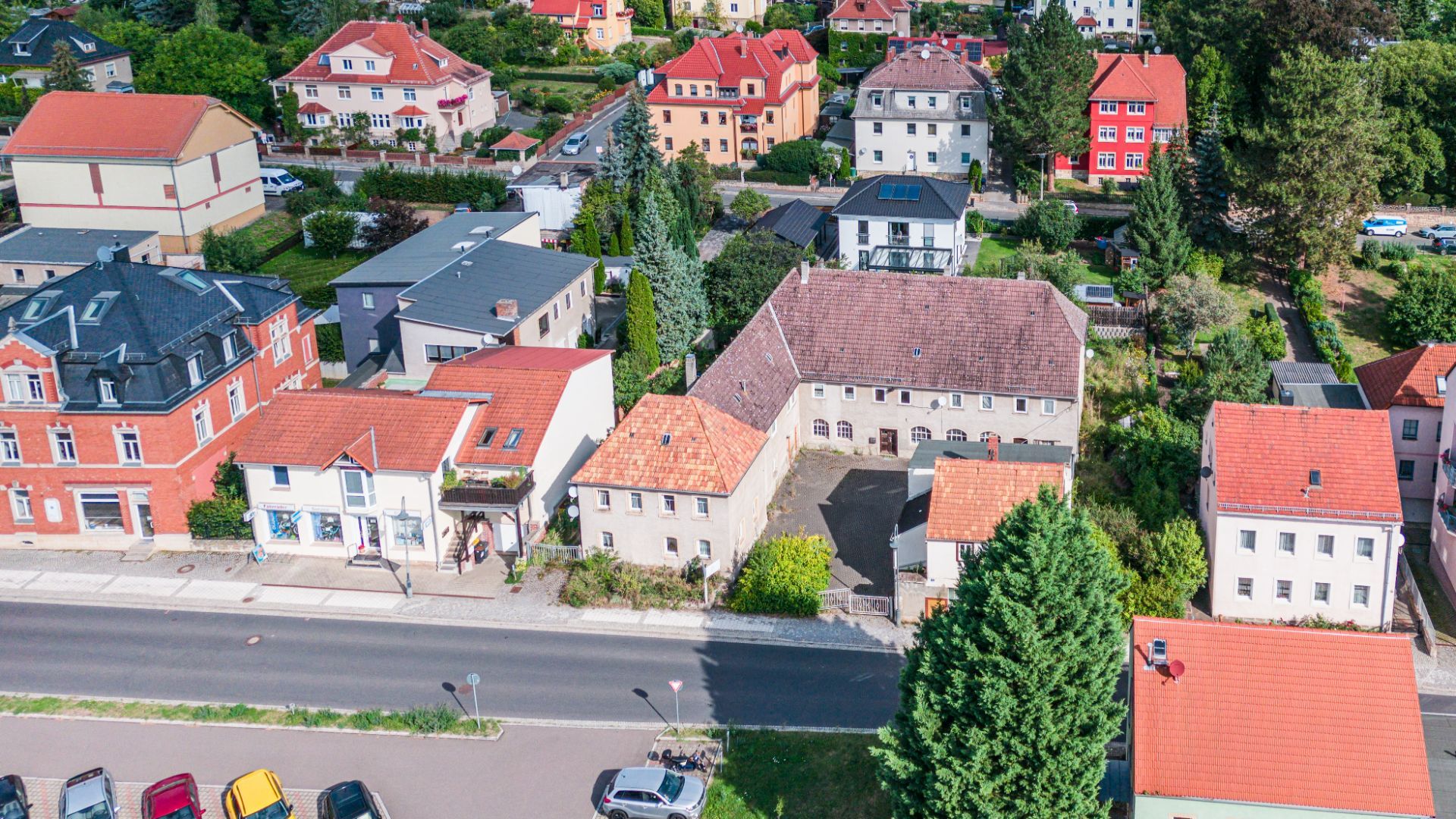 Luftaufnahme mehrerer Wohnhäuser mit roten Dächern und umliegenden Gärten.