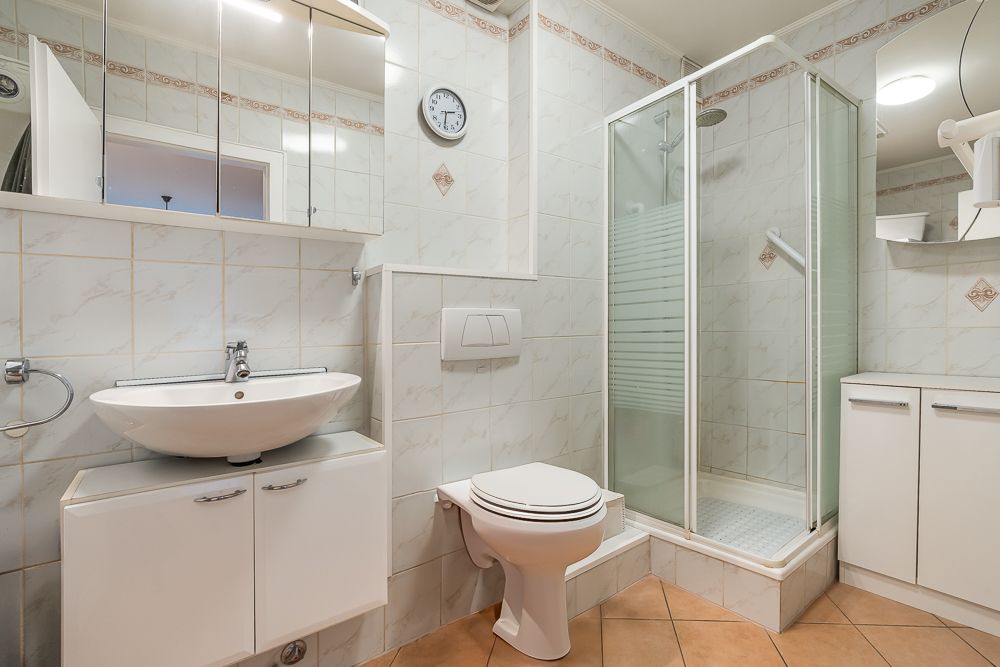 Modernes Badezimmer mit Dusche, WC, Waschbecken und Spiegelschrank.