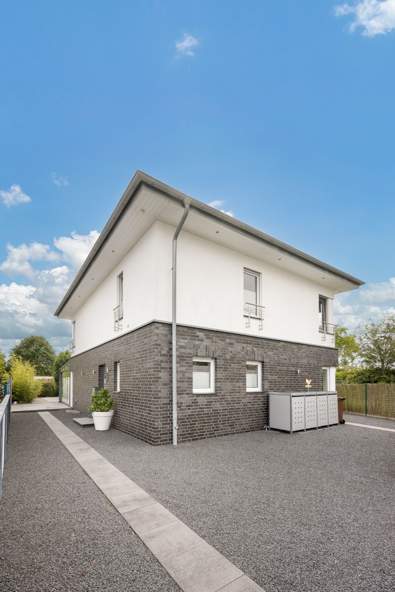 Modernes zweistöckiges Wohnhaus mit dunkler Klinkerfassade und hellem Obergeschoss.