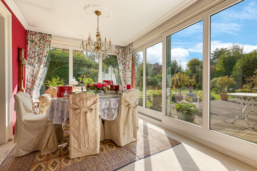 Heller Essbereich mit runden Tisch, sechs Stühlen und großen Fenstern zum Garten.