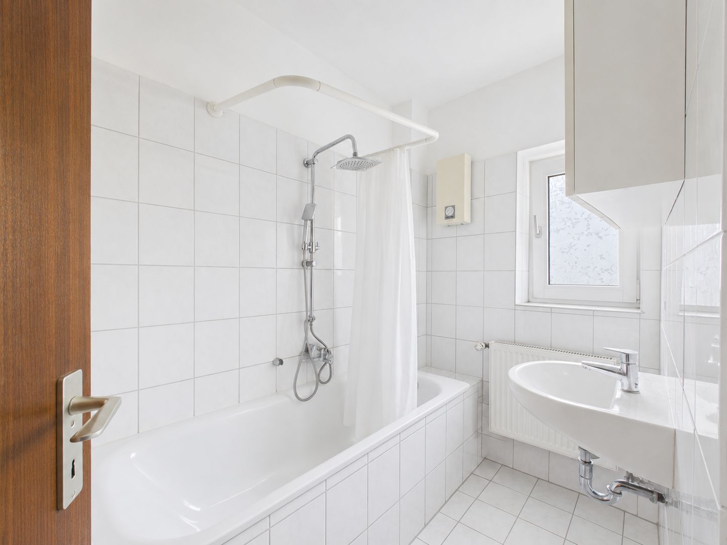 Helles Badezimmer mit Badewanne, Duschvorhang, Waschbecken und Fenster.