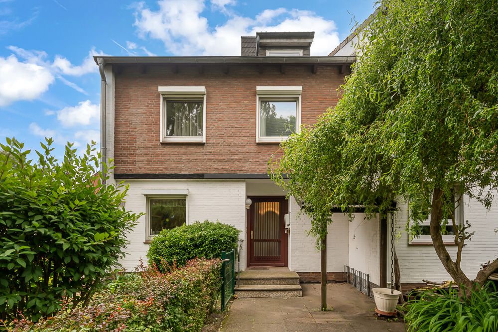 Zweistöckiges Wohnhaus mit roter Backsteinfassade, Garten und kleinem Eingangsbereich.