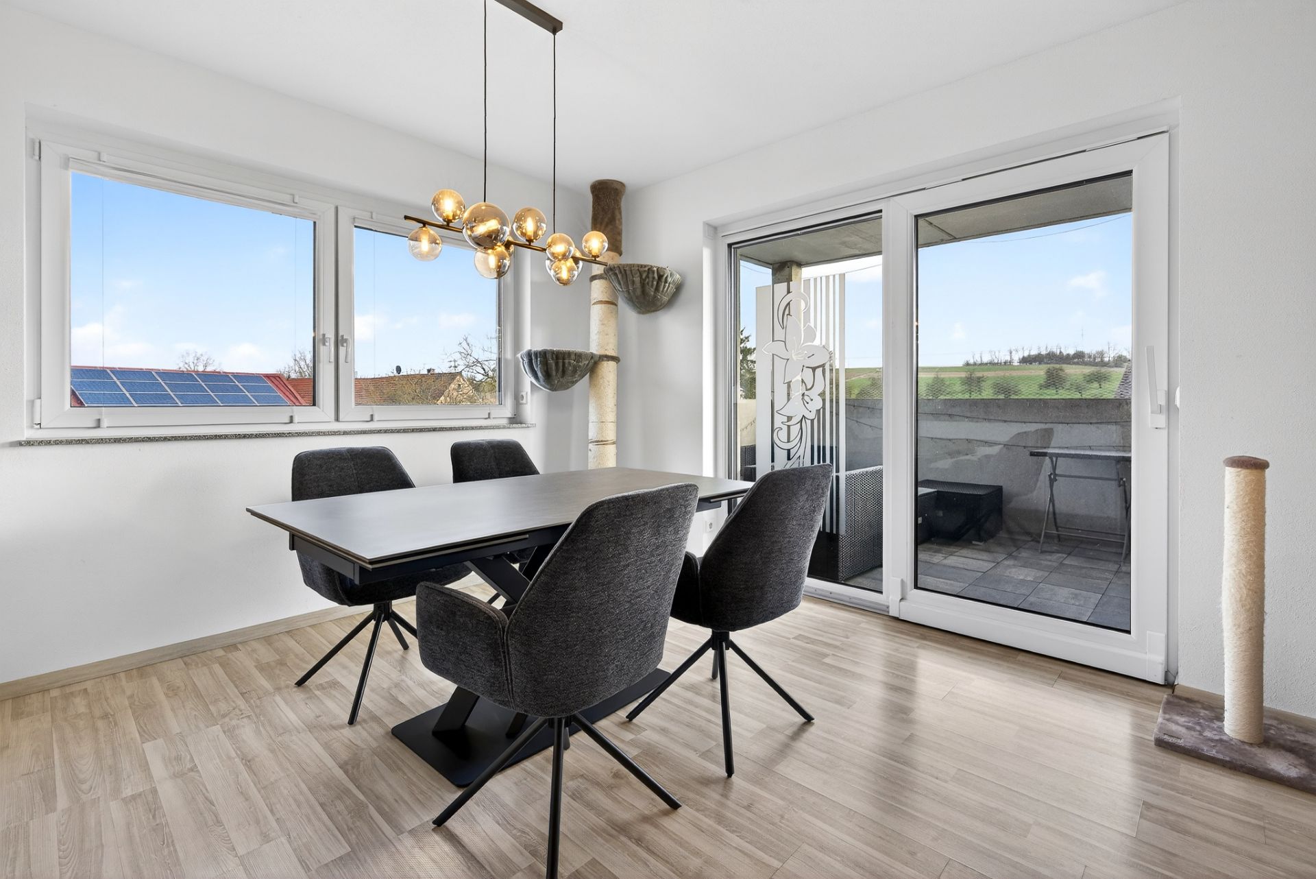 Essbereich mit vier dunklen Stühlen, großem Tisch, Fenster und Zugang zum Balkon.