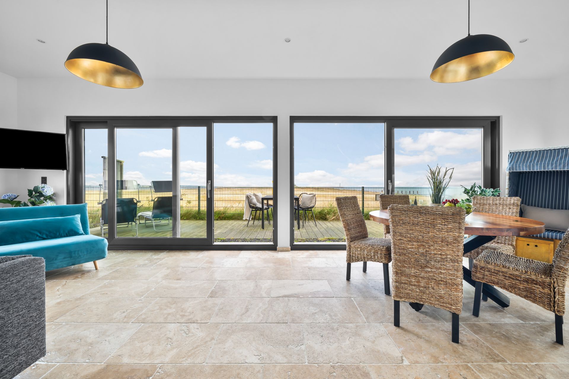 Helles Wohnzimmer mit Essbereich, großen Fenstern und Zugang zur Terrasse mit Ausblick ins Freie.