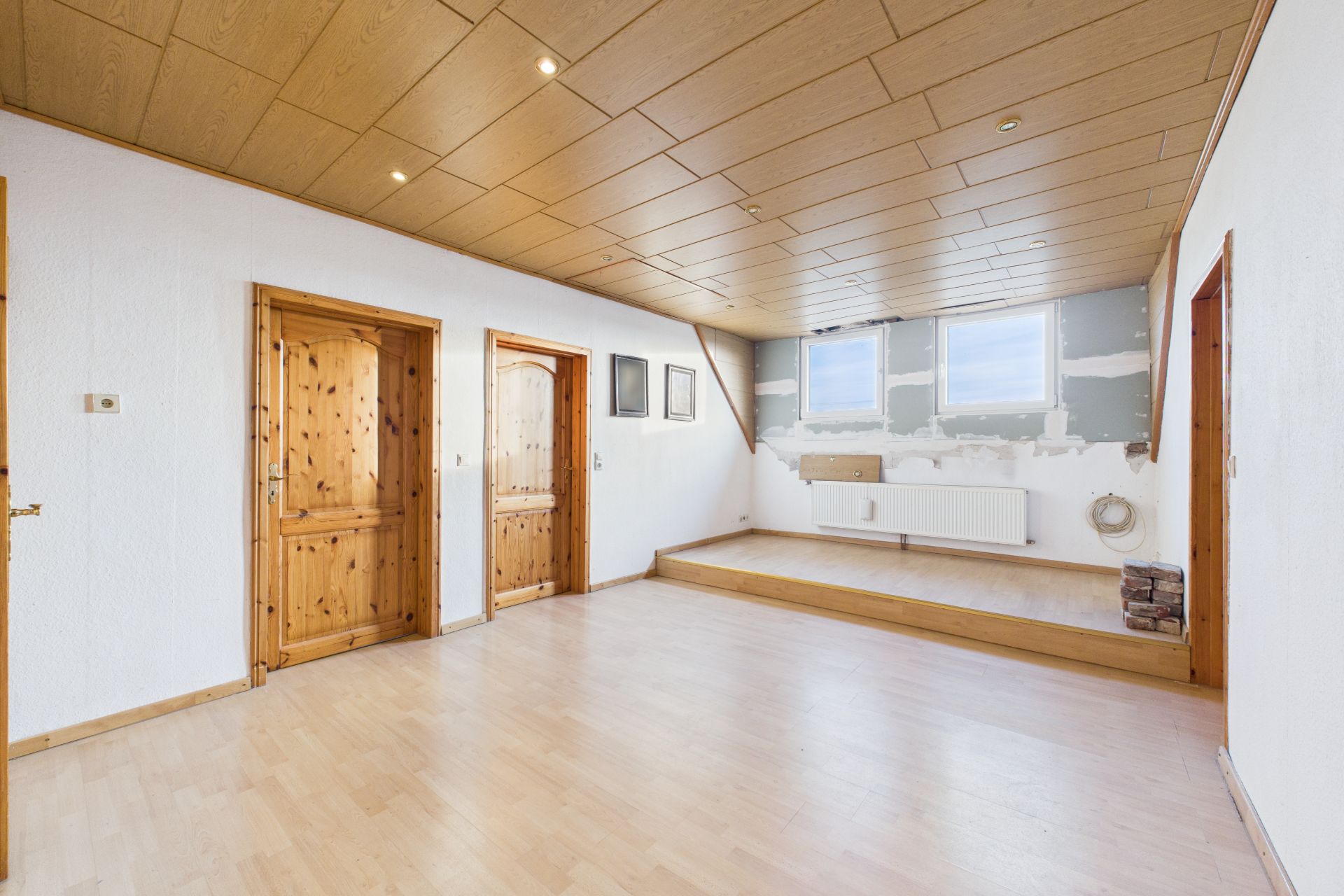 Heller Raum mit Holzdecke, Holztüren, hellem Boden und erhöhter Fensterfläche.