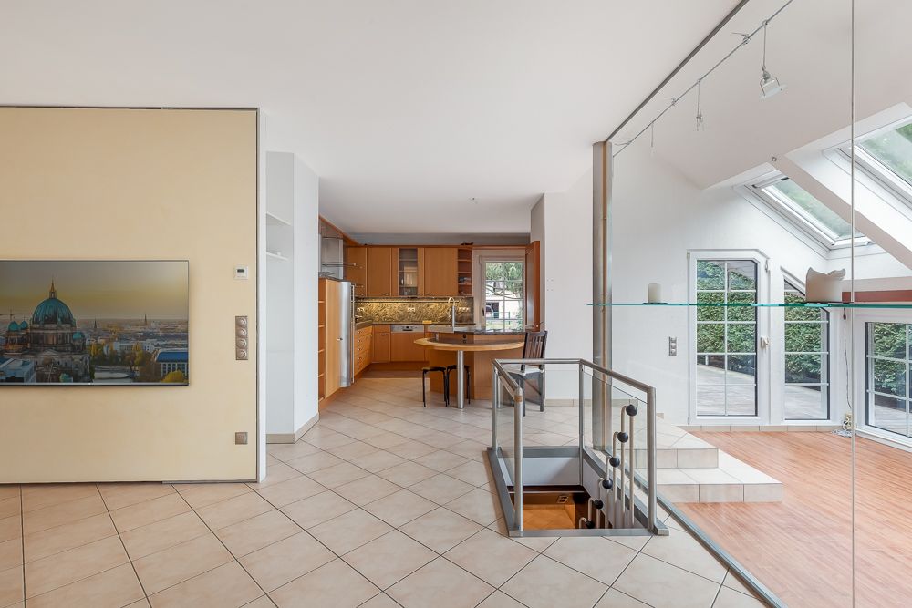 Helle Wohnküche mit Esstisch, Treppe, Glastüren und Zugang zur Terrasse.