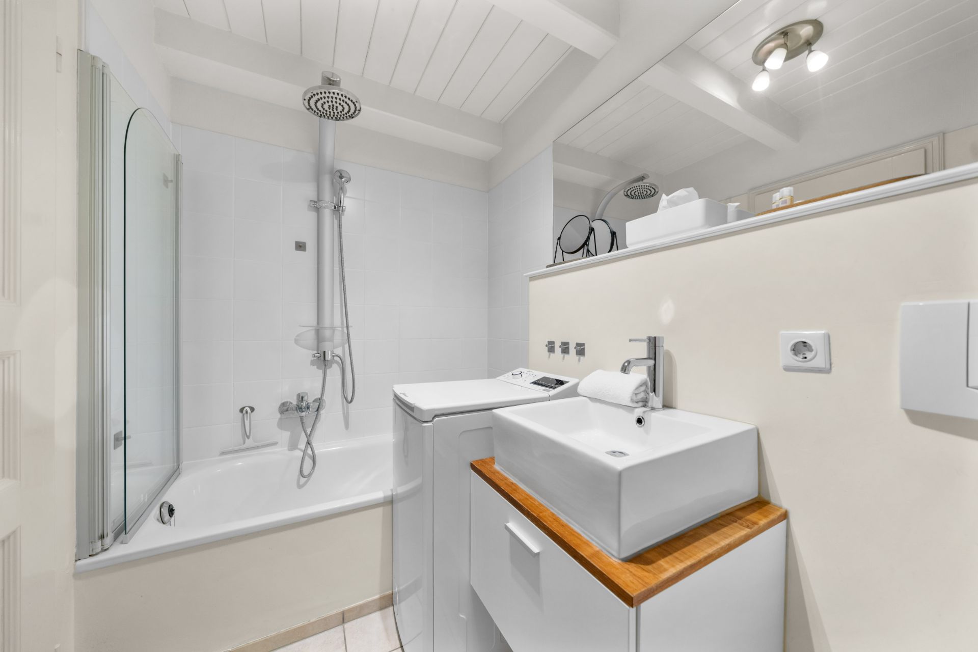 Modernes Badezimmer mit Badewanne, Waschbecken, Spiegel und Waschmaschine.