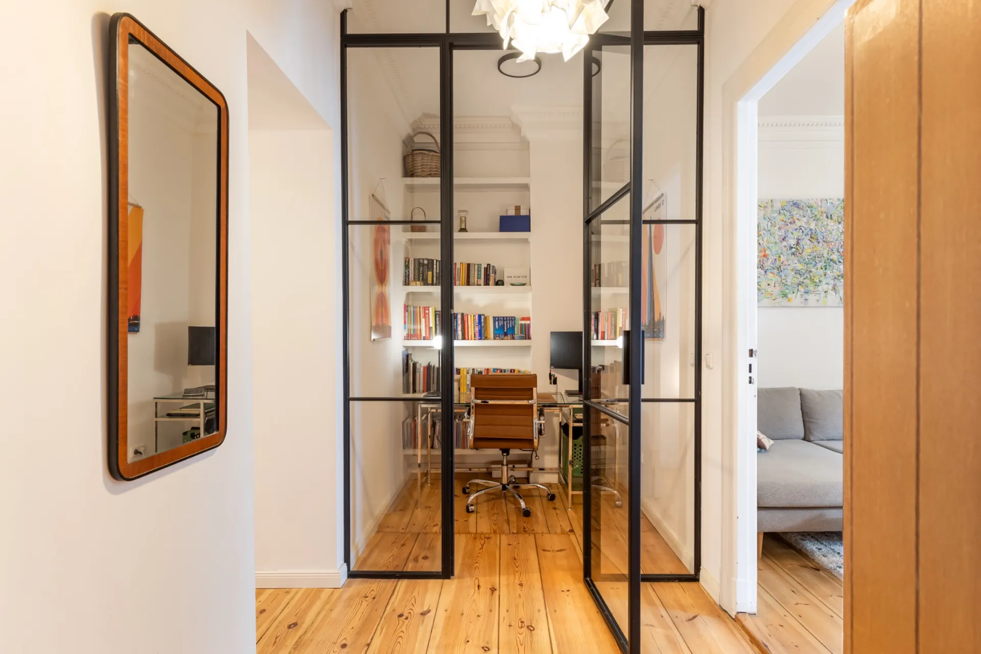 Flur mit Glastüren, dahinter ein Arbeitszimmer mit Bücherregalen, Schreibtisch und Stuhl.