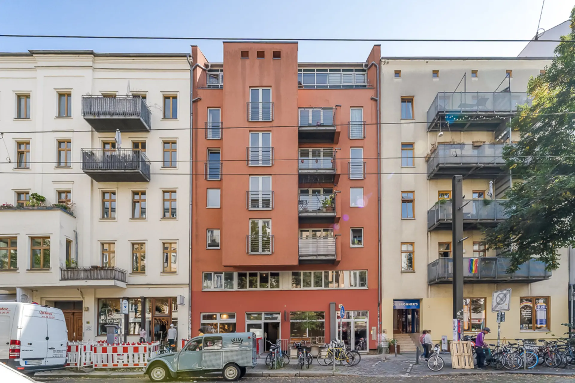 Mehrstöckiges Wohnhaus mit roten und beigen Fassaden, Balkonen und Fahrrädern davor.