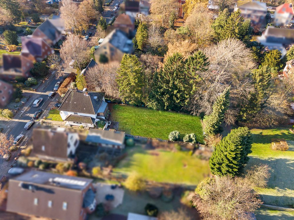 Luftaufnahme eines Einfamilienhauses mit großem Garten und umgebenden Bäumen in Wohngegend.