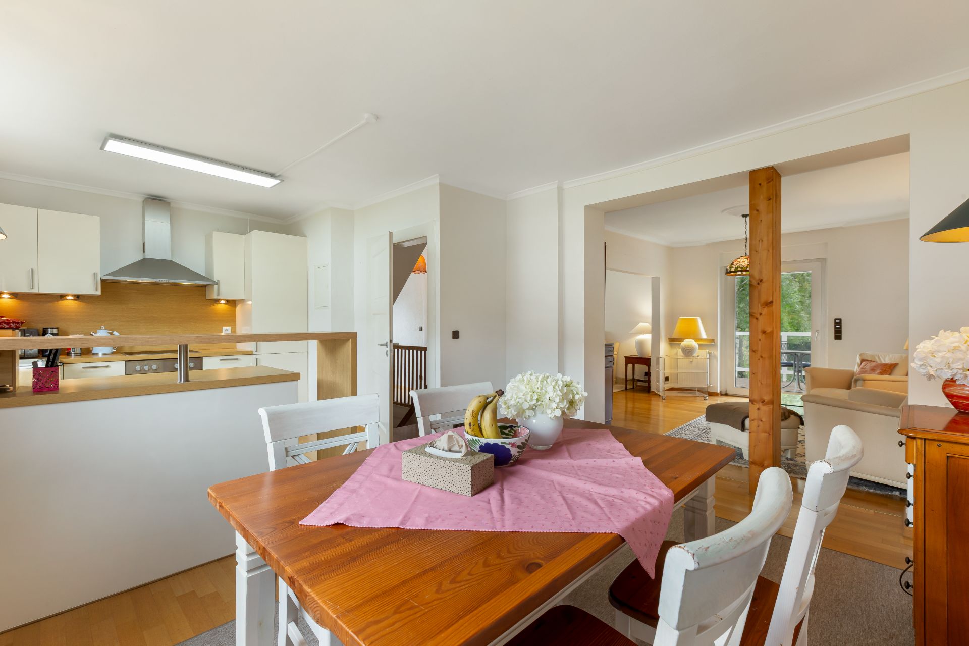 Essbereich mit Holztisch und vier Stühlen, offene Küche und angrenzendes Wohnzimmer sichtbar.